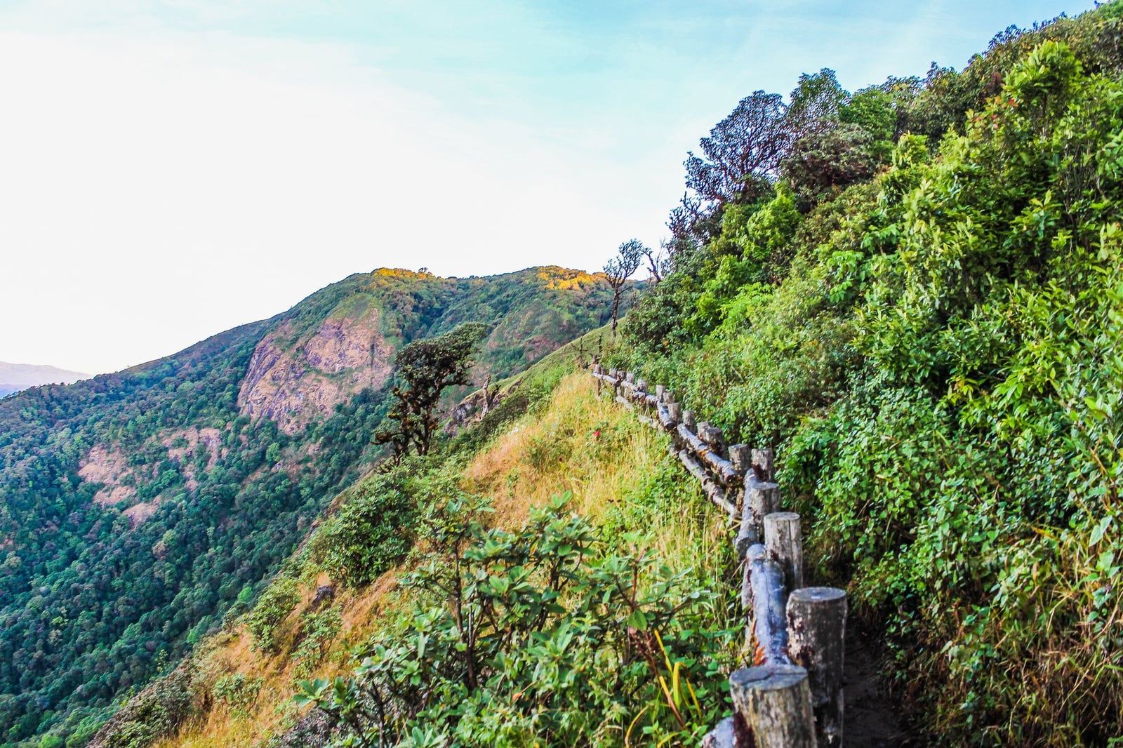 A wooden post-and-rail fence lines the scenic mountain ridgeline trail at Kew Mae Pan in Doi Inthanon National Park.