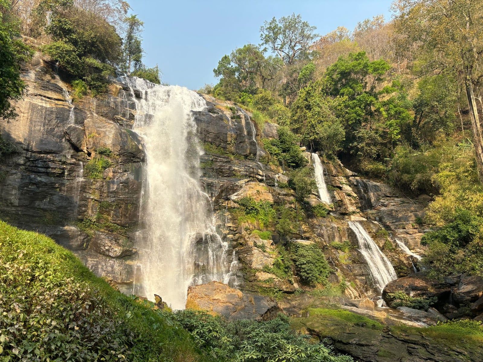 Wachirathan Waterfall flowing down a steep rock cliff surrounded by greenery in Doi Inthanon National Park.